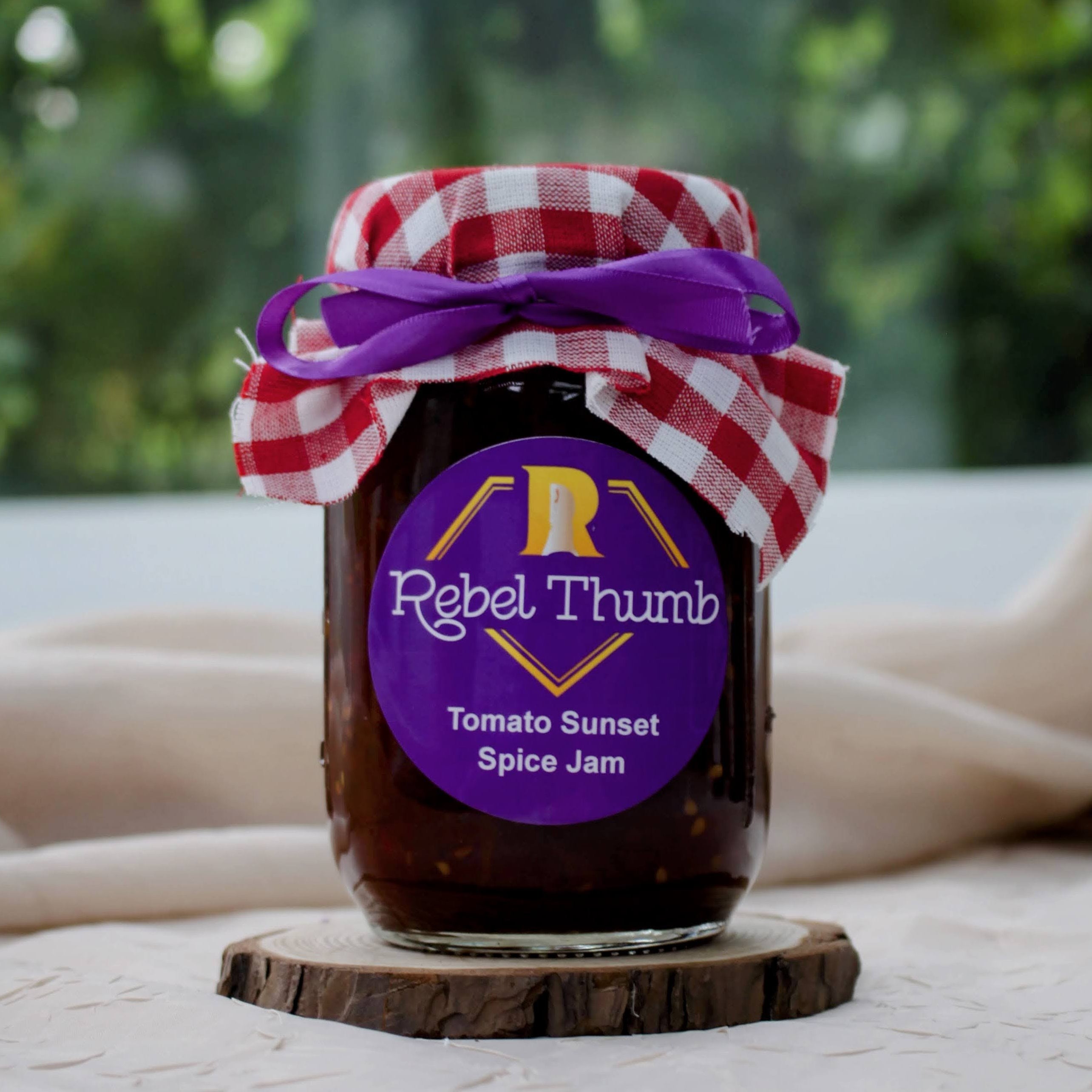 Jar of organic Rebel Thumb Tomato Sunset Spice Jam made in California with a purple label