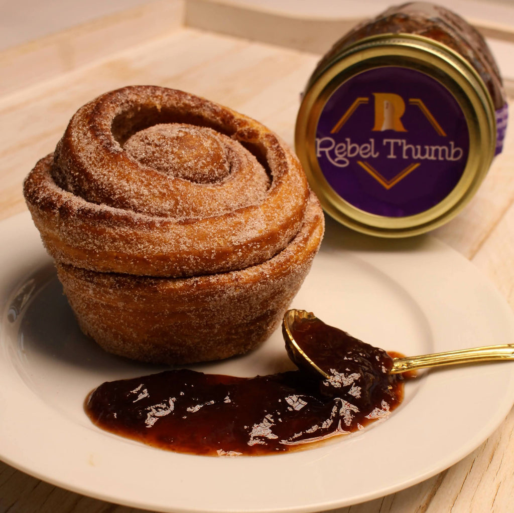 Cinnamon roll dessert with spoonful of organic jam made in California with a purple Rebel Thumb label