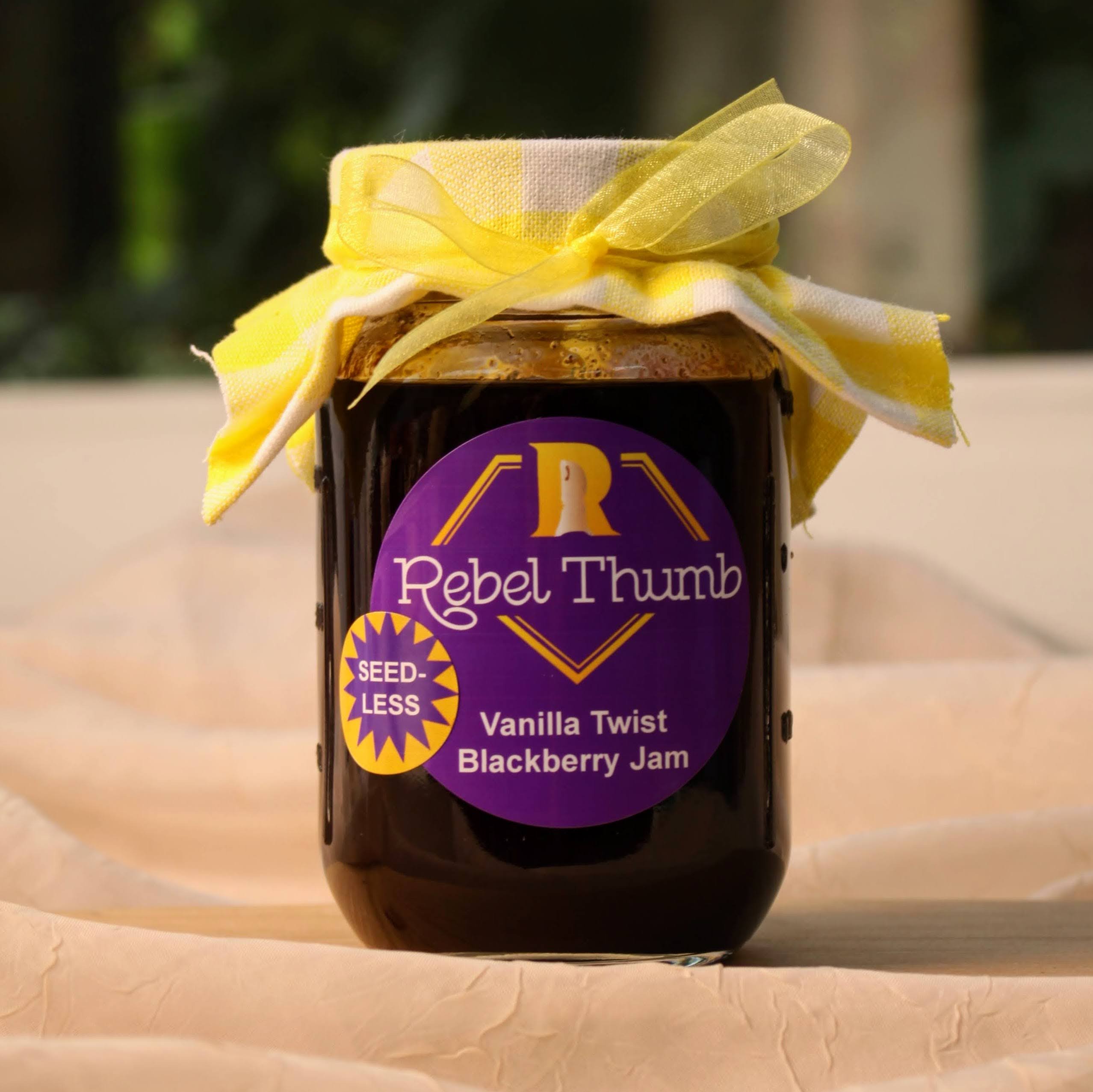 Jar of organic Rebel Thumb seedless Vanilla Twist Blackberry Jam made in California with a yellow ribbon