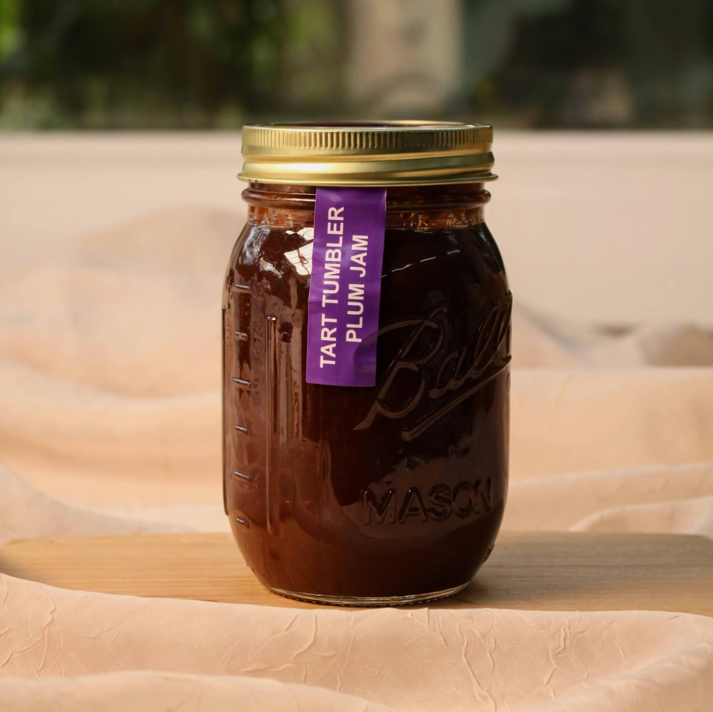 Jar of organic Tart Tumbler Plum Jam made in California with a purple label on a wooden surface